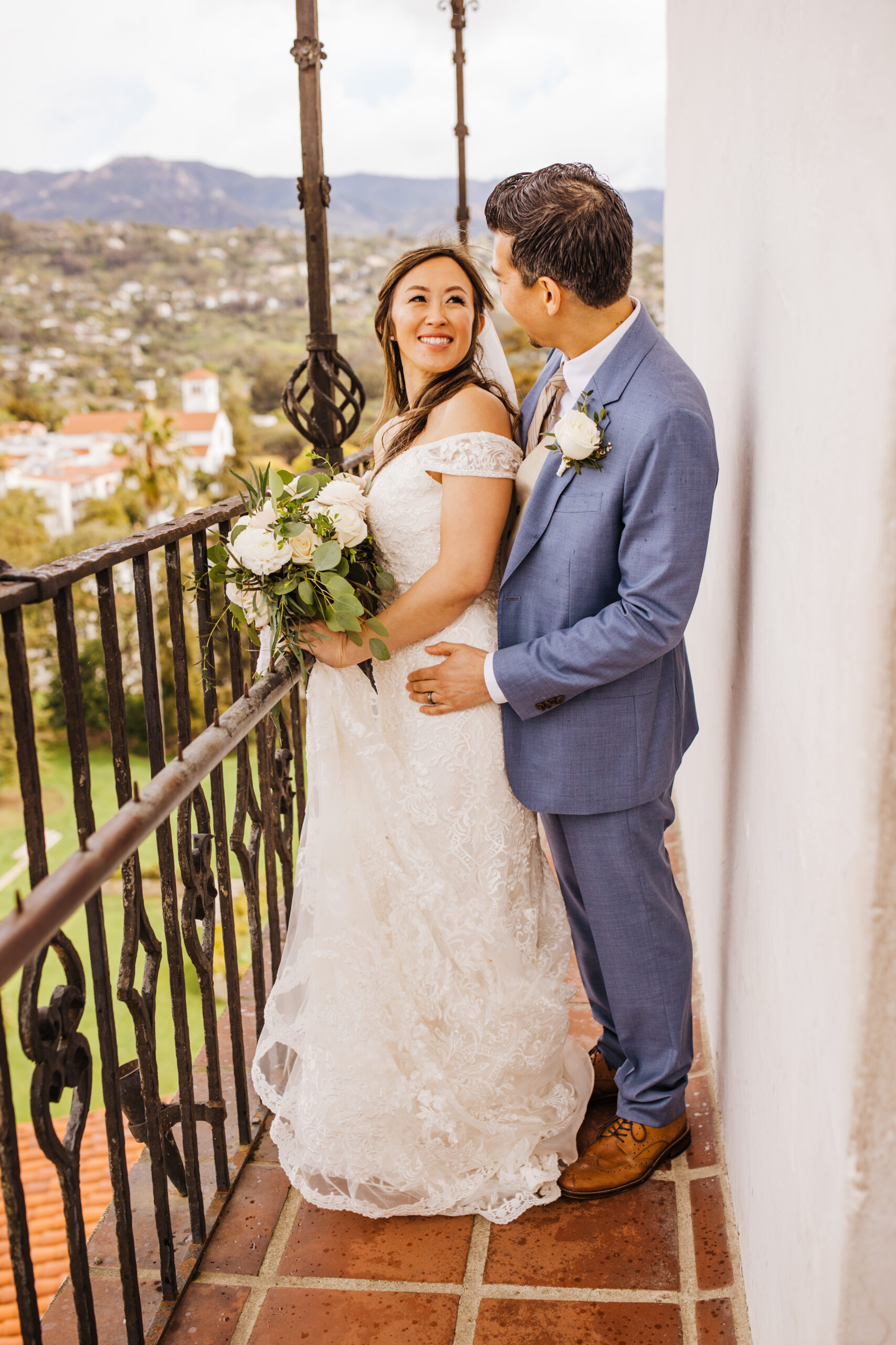 bride and groom on balcony with view of Santa Barbara below