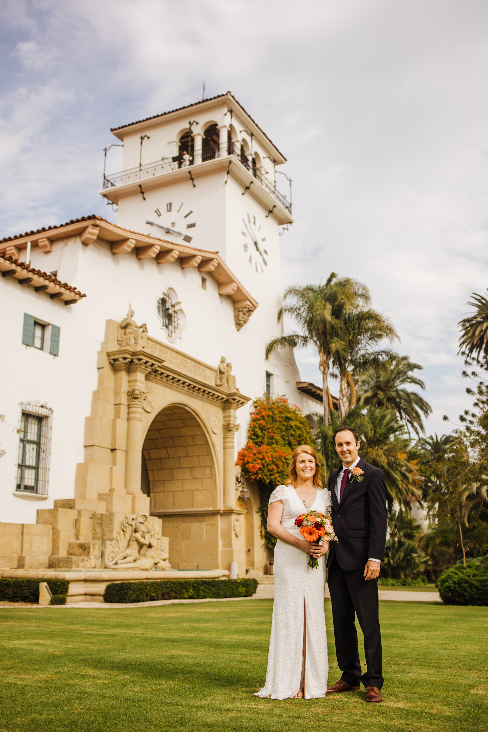 bride and groom posed on lawn in front of SB County Courthouse