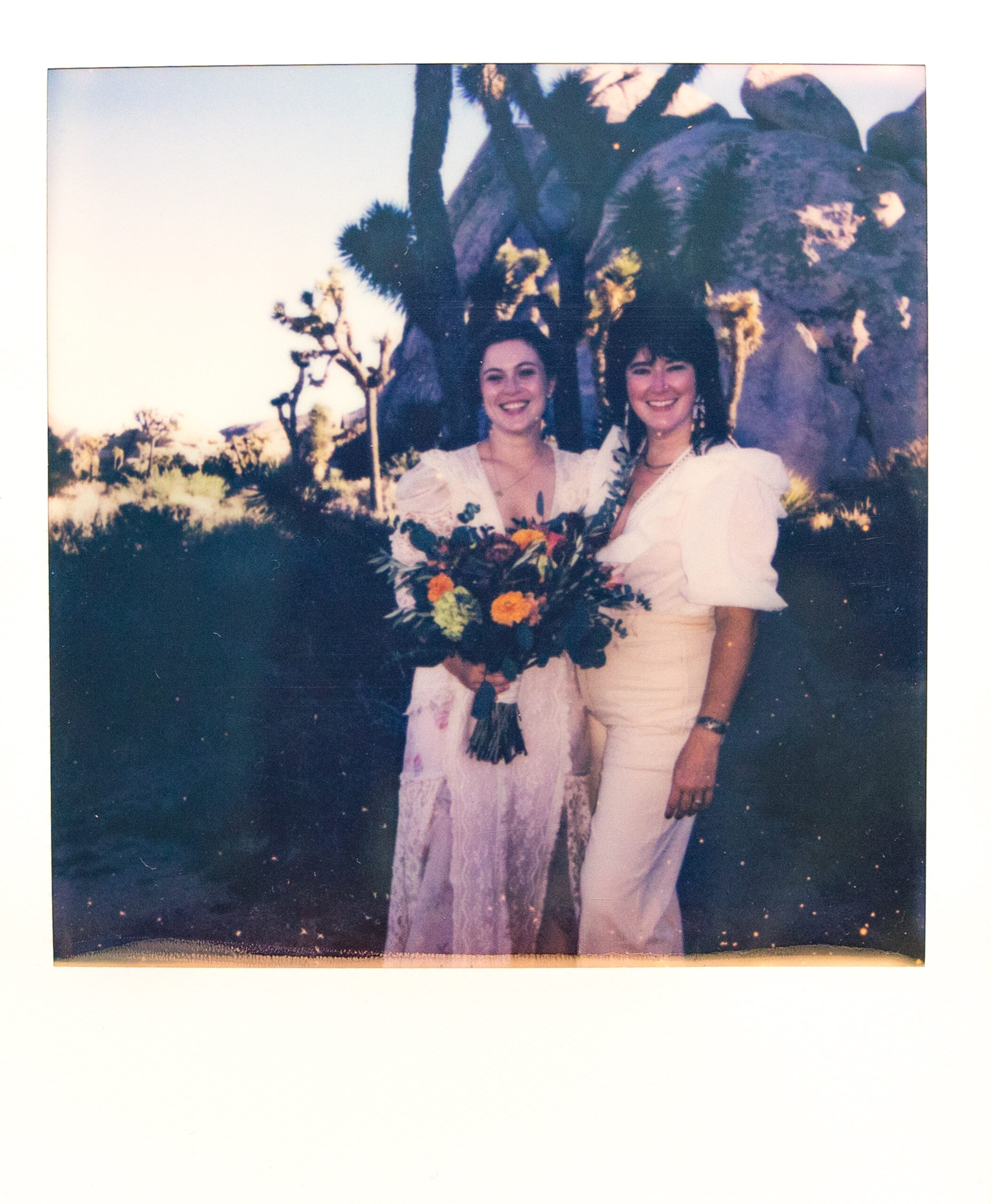 Two brides smiling in Joshua Tree Polaroid