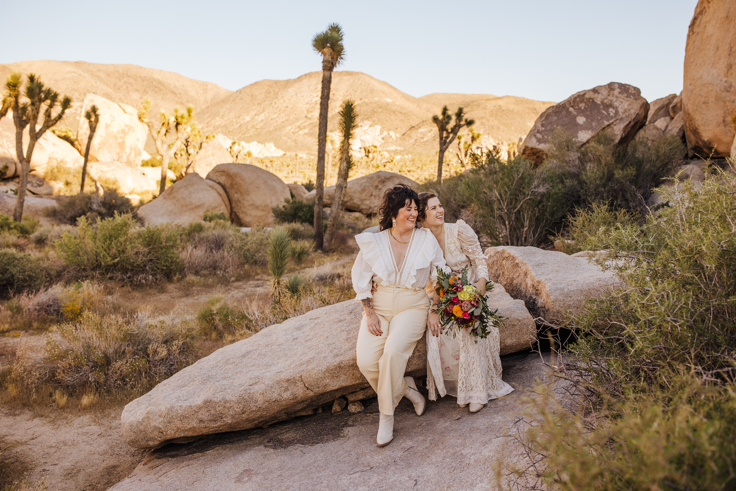 Two brides sitting on rock in Joshua Tree National Park
