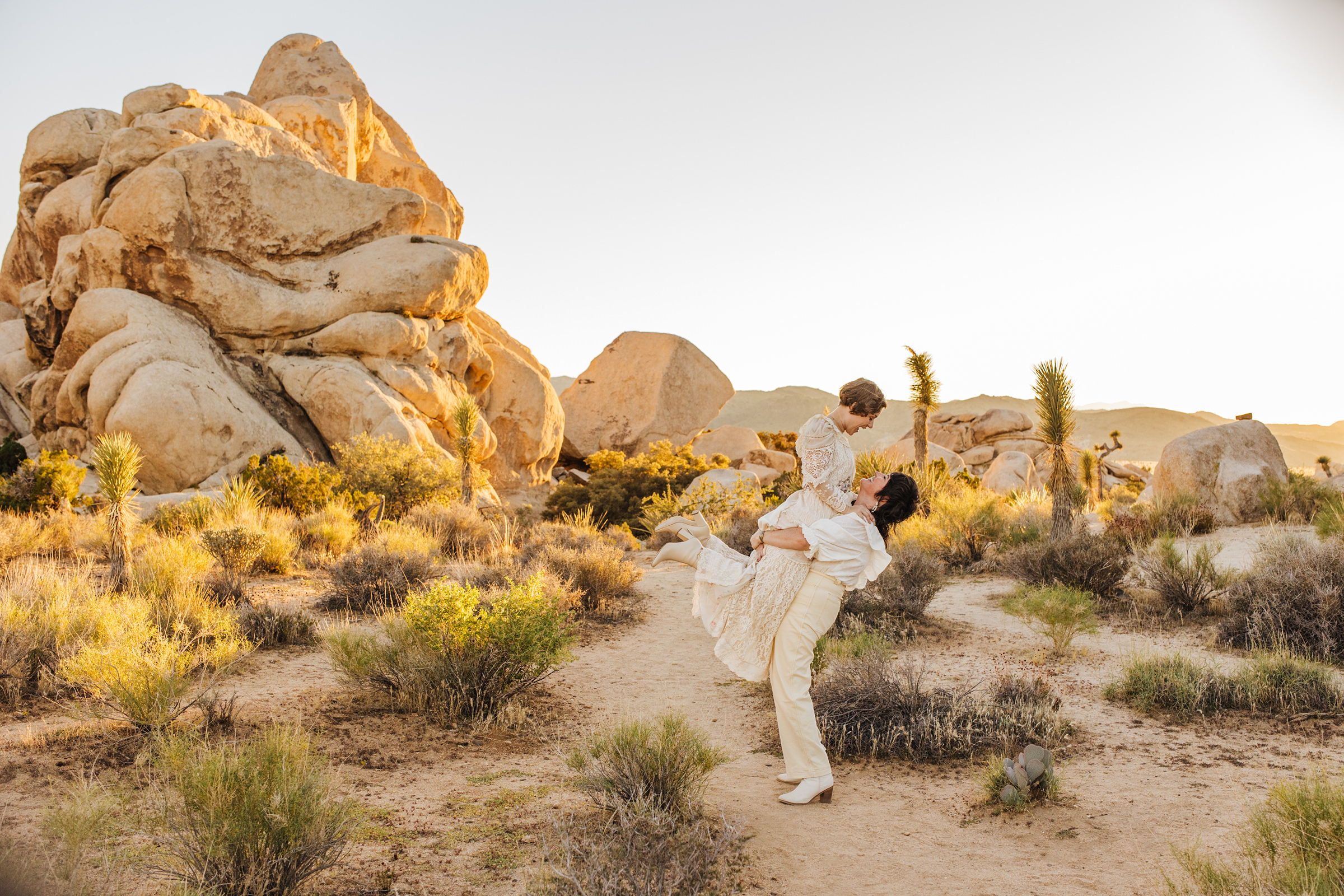 One bride lifting another into the air in Joshua Tree