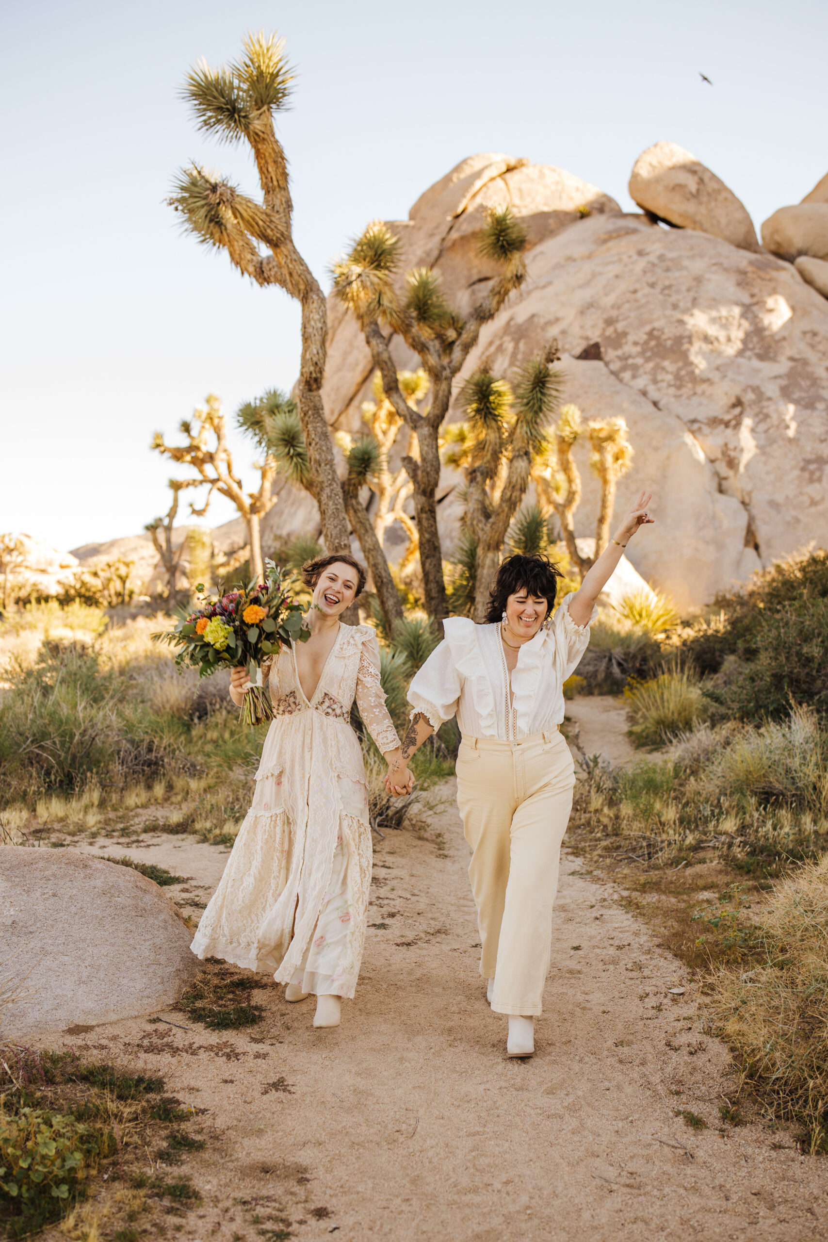 Two brides cheering after their Joshua Tree elopement ceremony